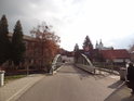 Obloukový silniční most přes Divokou Orlici v Žamberku, v pozadí dvojice věží kostela svatého Václava.
